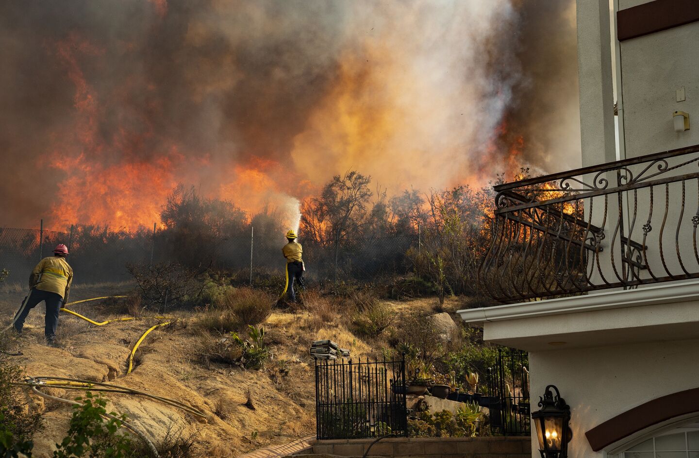 Firefighters battle to save a home from a wall off flames as the Holy fire continues to burn out of control in Lake Elsinore, Calif.