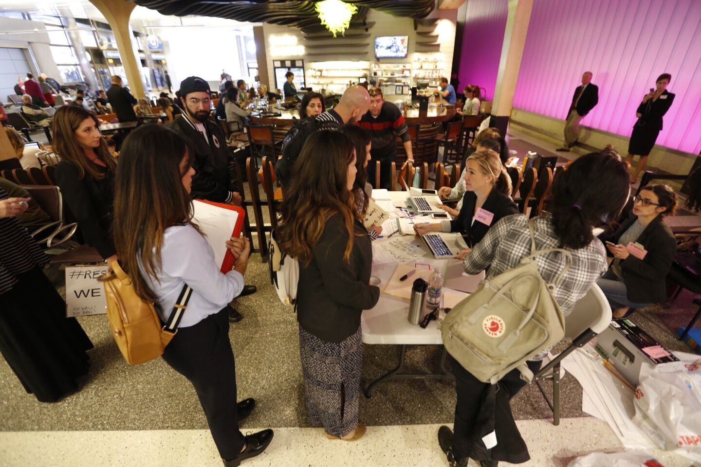 Attorney's crowd a small table at the Tom Bradley International Terminal at LAX on Monday to assist travelers who require help due to President Trump’s travel restrictions.