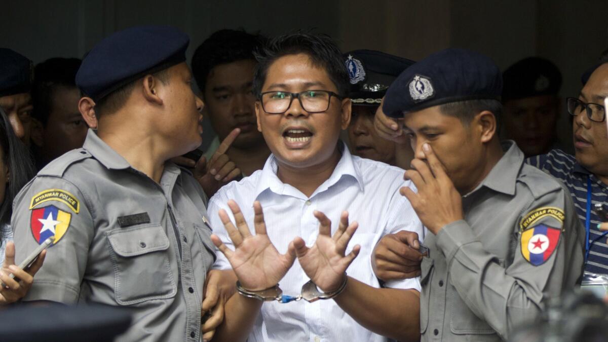 Reuters journalist Wa Lone talks to reporters as he is escorted by police from a court in Yangon, Myanmar, on Sept. 3, 2018.