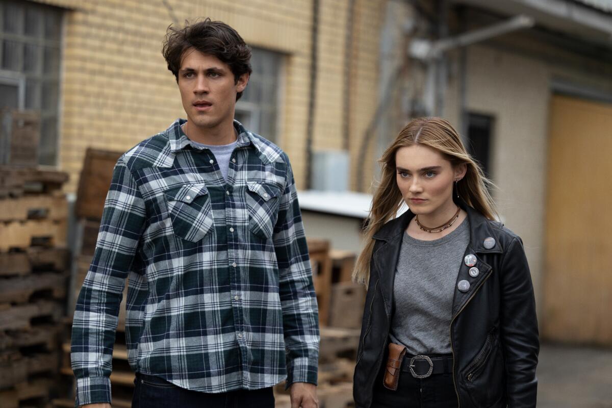 A man in a flannel, left, and a girl in a leather jacket looking angry 