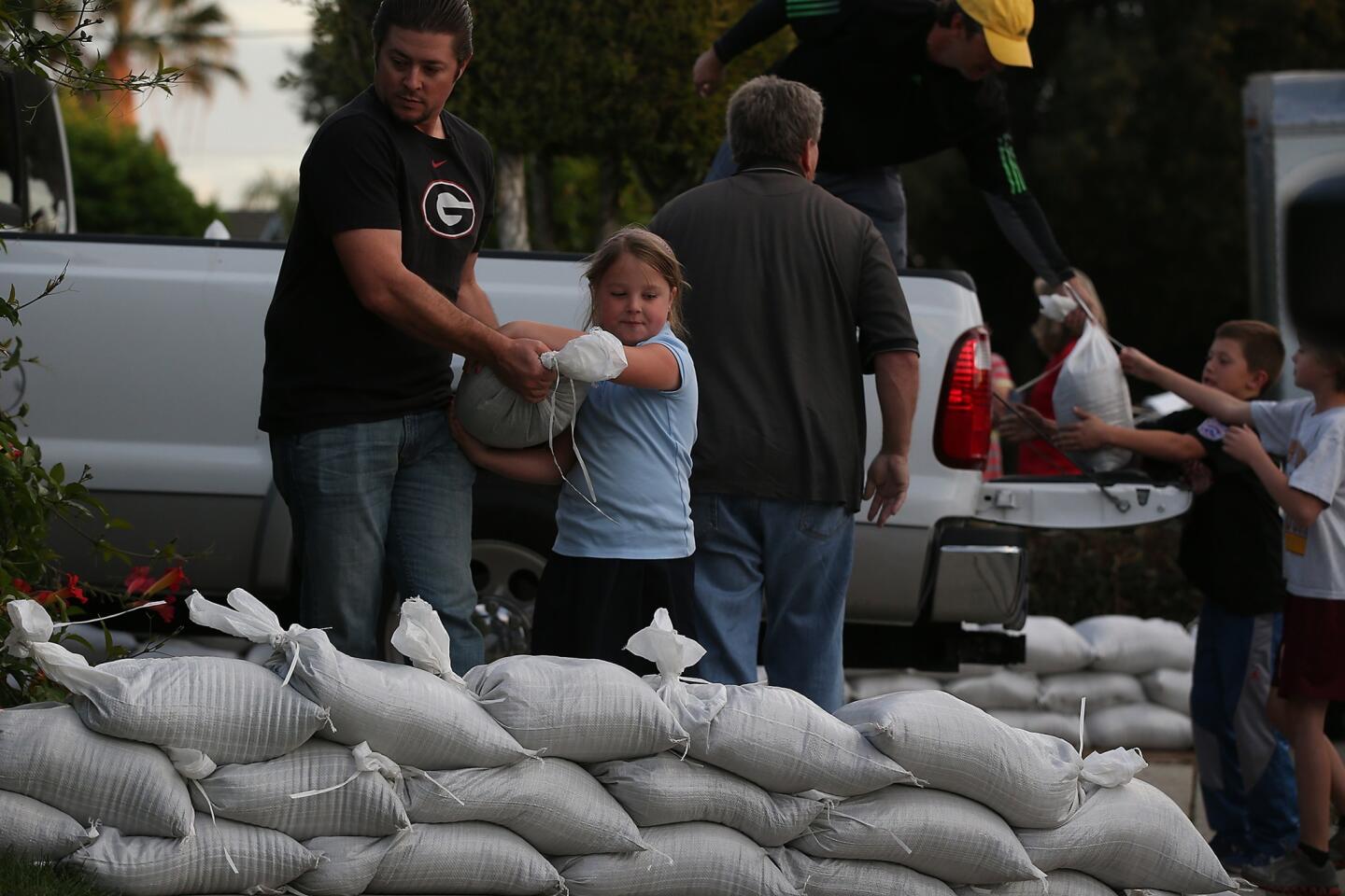 Glendora residents Ryan Dickey and his daughter, Jenna, 7, place sandbags outside a home on Loraine Avenue to help protect it against possible flooding near the site of January's Colby fire.