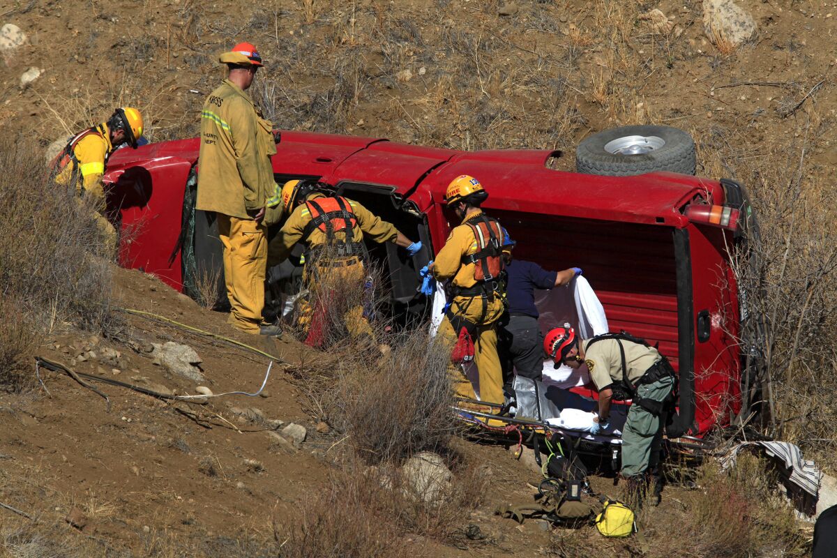Firefighters remove the dead and injured from a truck that plunged 200 feet down an embankment early Friday in Santa Clarita.