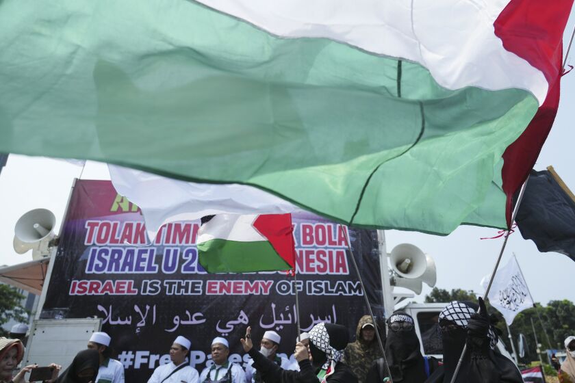A woman waves a Palestinian flag during a protest in Jakarta, Indonesia, Monday, March 20, 2023. Hundreds of conservative Muslims have marched to the streets Monday in Indonesia's capital to protest against the Israeli team's participation in the FIFA World Cup Under-20 in Indonesia.(AP Photo/Achmad Ibrahim)