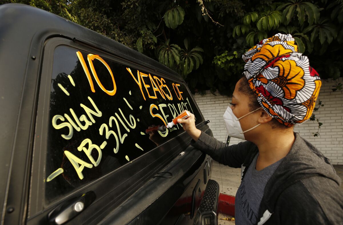 Courtney Banks writes on vehicle windows in support of workers who lost their jobs.