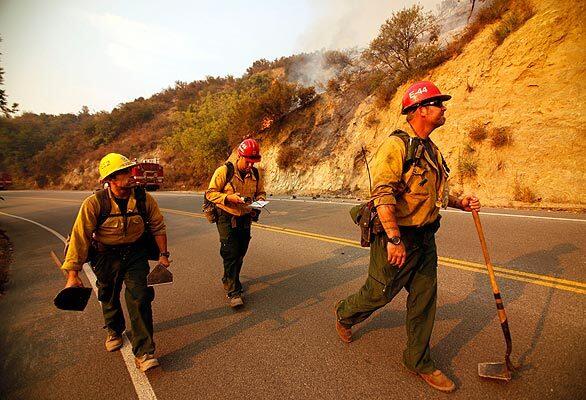 Forest service fire Capt. Mike Scott, right, with firefighters Joe Valencia, left, and Armando Pina walk along Angeles Crest Highway above La Ca?ada Friday morning to assess the Station fire. Friday will be hot again, with temperatures hovering near 100 degrees.