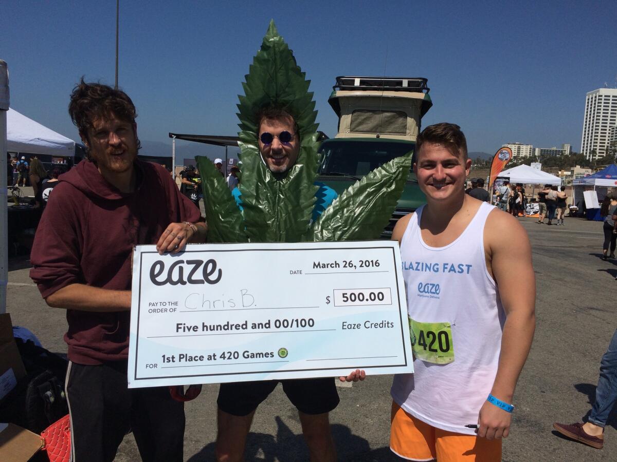 Chris Barnicle, left, winner of the 420 Games in Santa Monica on Saturday, receives a check for $500 in medical marijuana from Eaze, the developer of a medical marijuana delivery app.