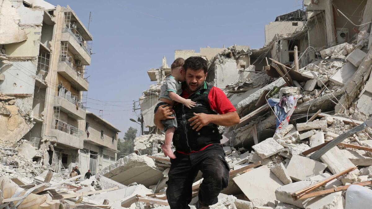 A Syrian man carries a child after removing him from the rubble of a destroyed building following a reported airstrike in the Qatarji neighborhood of the northern city of Aleppo on Wednesday.