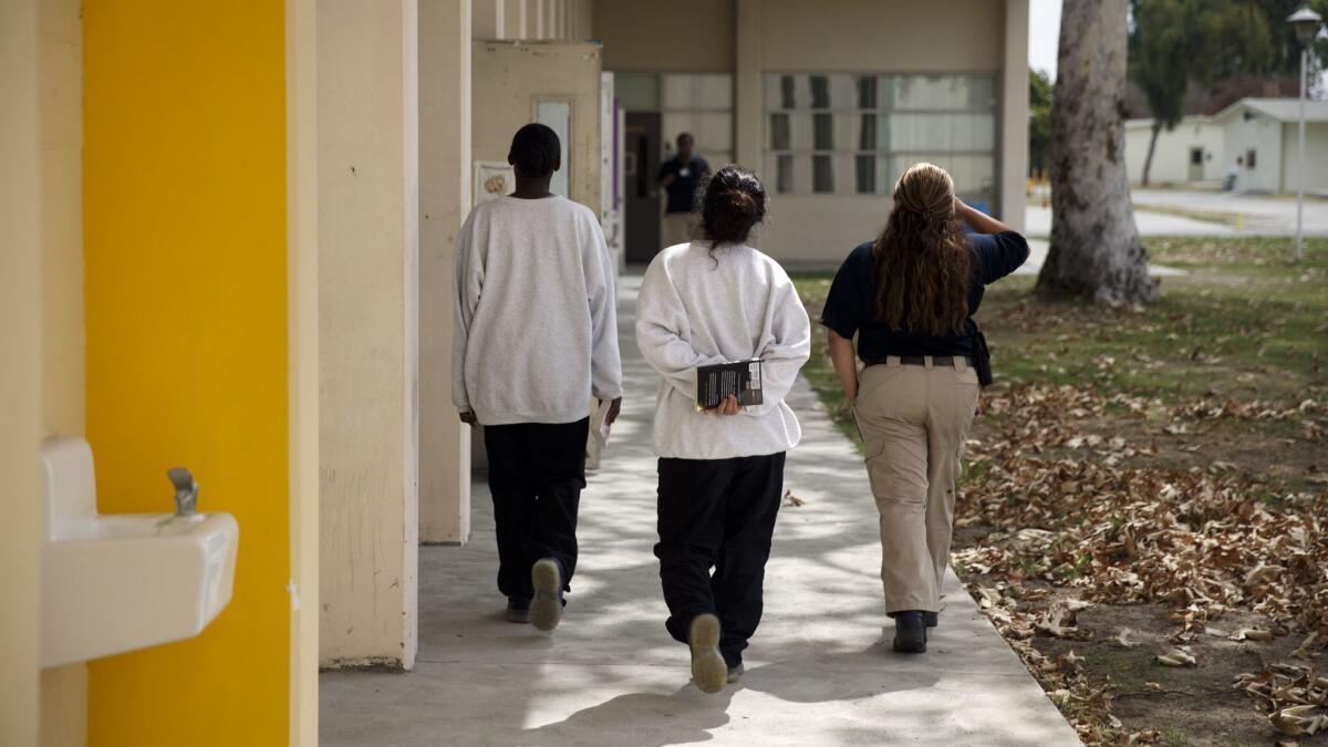 An officer escorts young women detained at Los Padrinos Juvenile Hall in Downey in 2016. Six detention officers have been charged with felonies and misdemeanors in connection with their use of pepper spray.