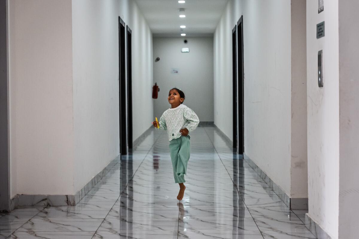 A little girl hops around on one leg down a hallway
