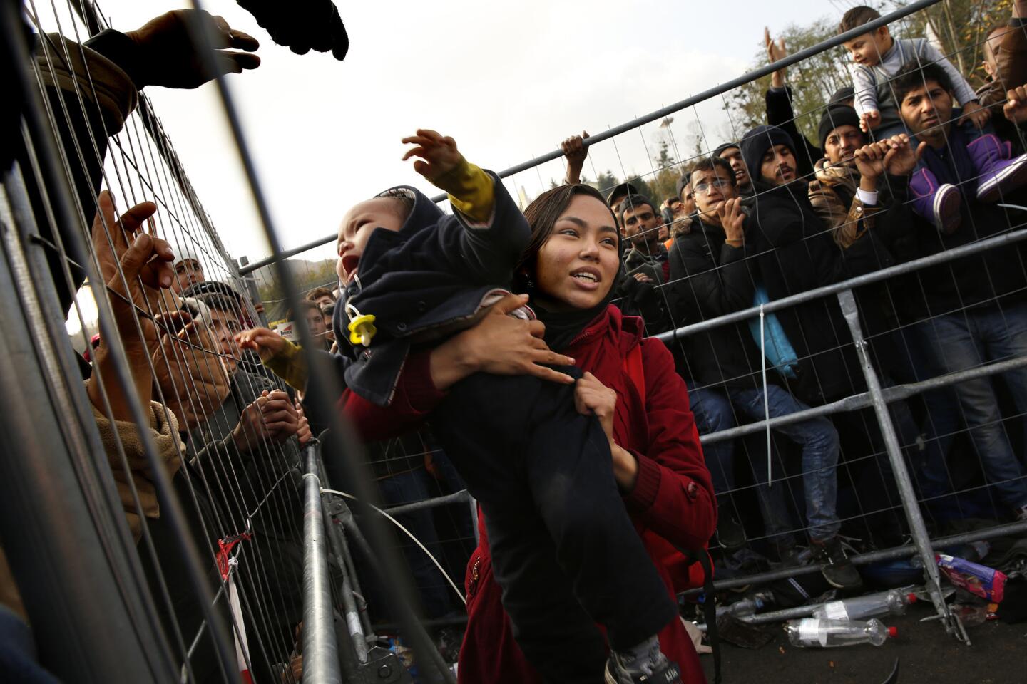 Narges Heydari, 15, catches her crying brother, Matin, 1, as he is lifted over the fence at the Austrian border. Narges climbed the fence first because of the crush of people. She arrived from Afghanistan with her parents and three siblings.