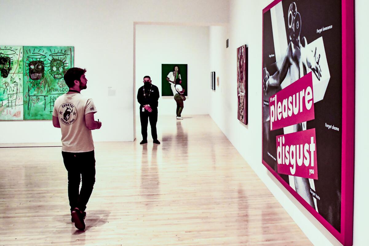 People in an art museum looking at paintings on the wall.