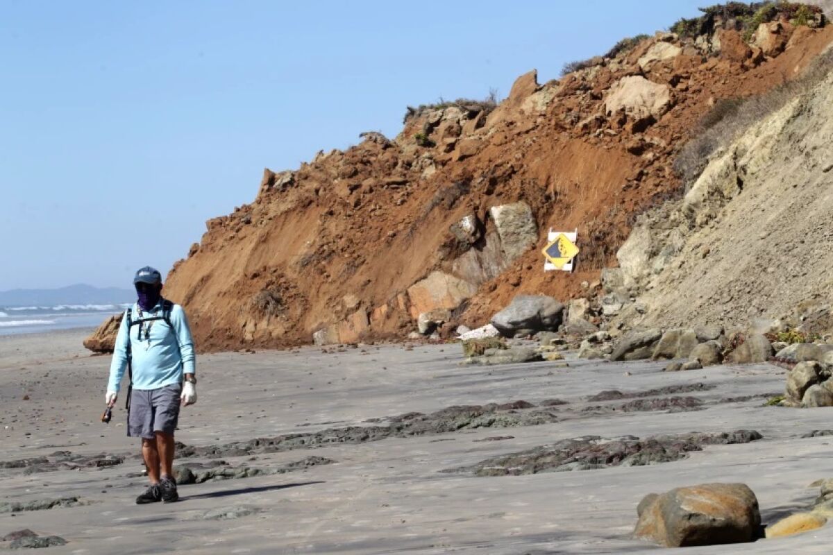 A man passes a section of coastal bluff which collapsed in Del Mar Sunday morning, Feb. 28.