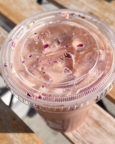 A Dirty Rose Girl (rose latte) in a clear plastic cup with a lid