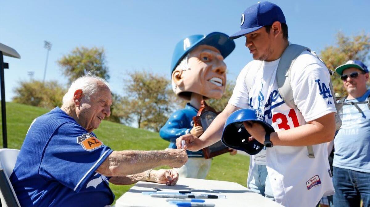 Former Dodgers manager Tommy Lasorda, left, signs an autograph for Alvaro Negrete, 21, of Oxnard, at Dodgers spring training camp in Glendale, Ariz., on Feb. 21.