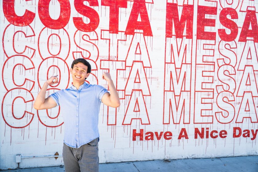 A man poses in front of a mural outside Social Kitchen + Craft Bar on Costa Mesa's 19th Street.