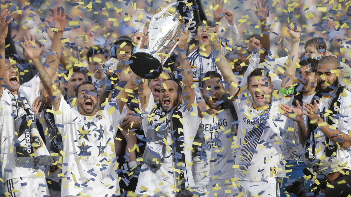 Galaxy forward Landon Donovan, center, holds the MLS Cup trophy after a 2-1 overtime win against the New England Revolution for the MLS title on Dec. 7, 2014.