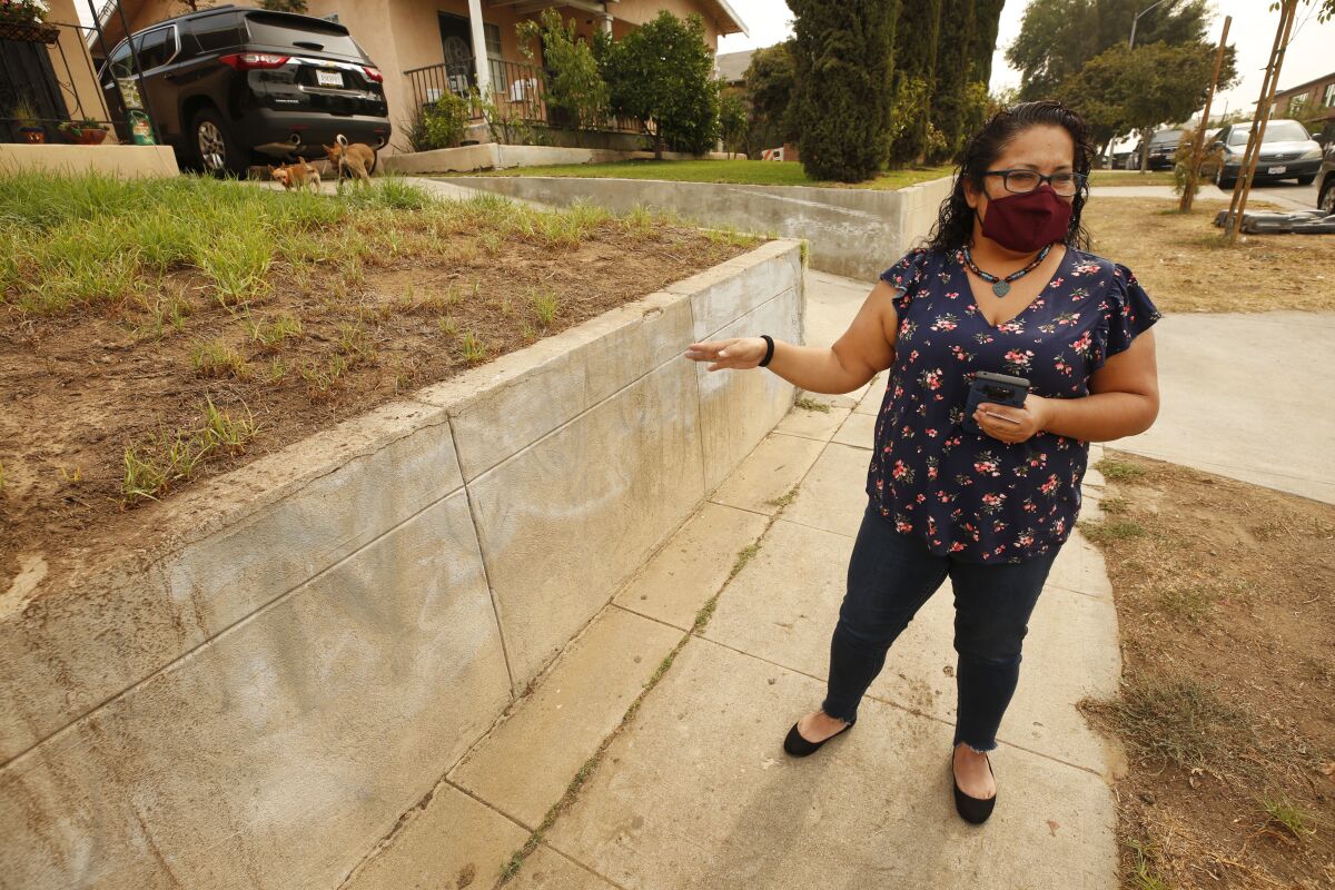 A woman stands on a sidewalk outside her home 