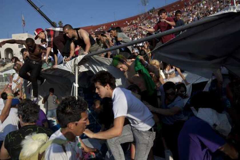 Attendees at the Electric Daisy Carnival rush a fence at the Los Angeles Memorial Coliseum.