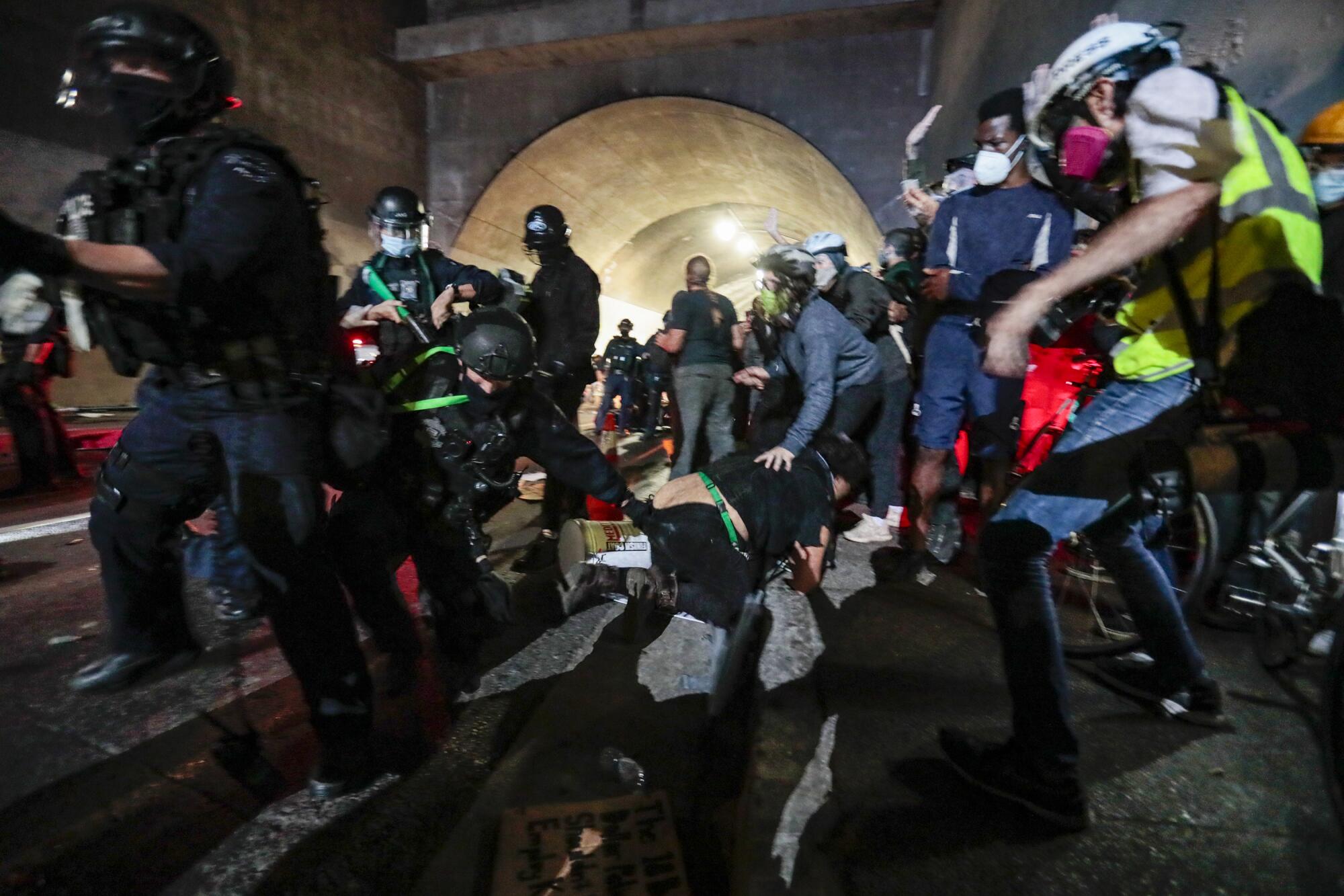 A protester is chased by an LAPD officer as police converge on demonstrators in the 3rd Street tunnel.