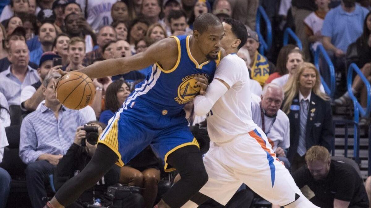 Warriors forward Kevin Durant works around Thunder forward Andre Roberson during the first half of a game on Feb. 11.
