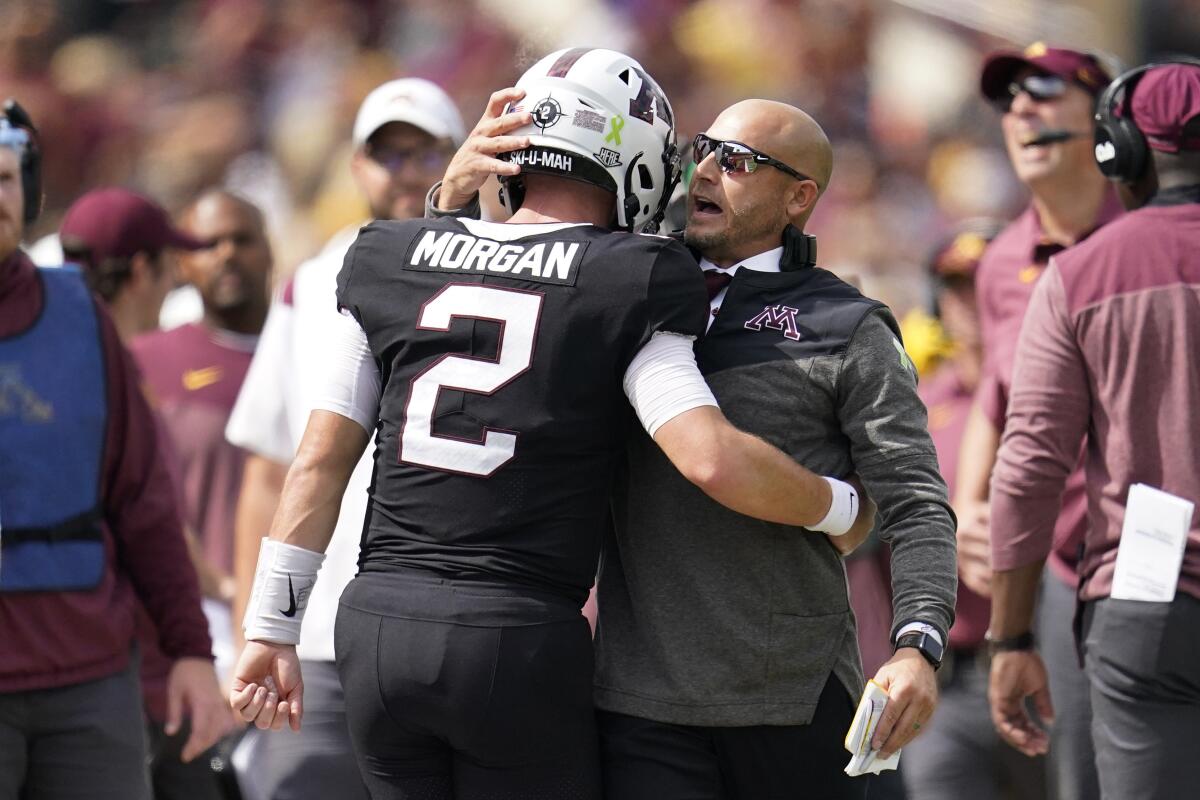 Minnesota quarterback Tanner Morgan, left, and head coach P. J. Fleck, right, hug after a Minnesota touchdown during the first half of an NCAA college football game against Western Illinois, Saturday, Sept. 10, 2022, in Minneapolis. (AP Photo/Abbie Parr)