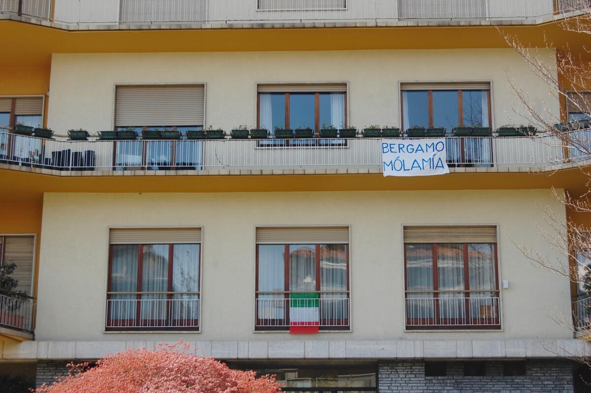 Residents of Bergamo, Italy, fly the Italian flag and display signs saying, "Don't give up, Bergamo."