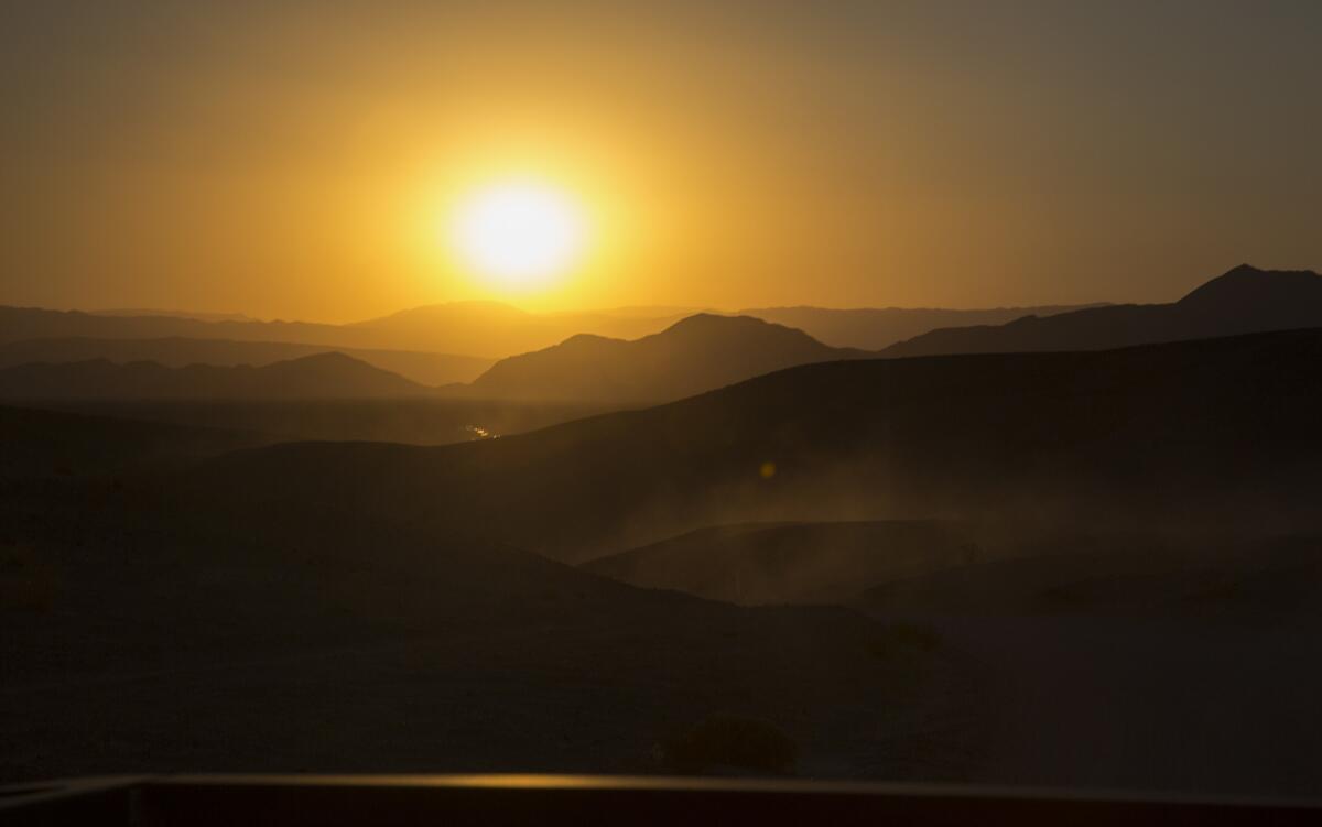 The sun sets over the mountain ridges and the Amargosa River in the Mojave Desert, near the Dumont Dunes in Silurian Valley.