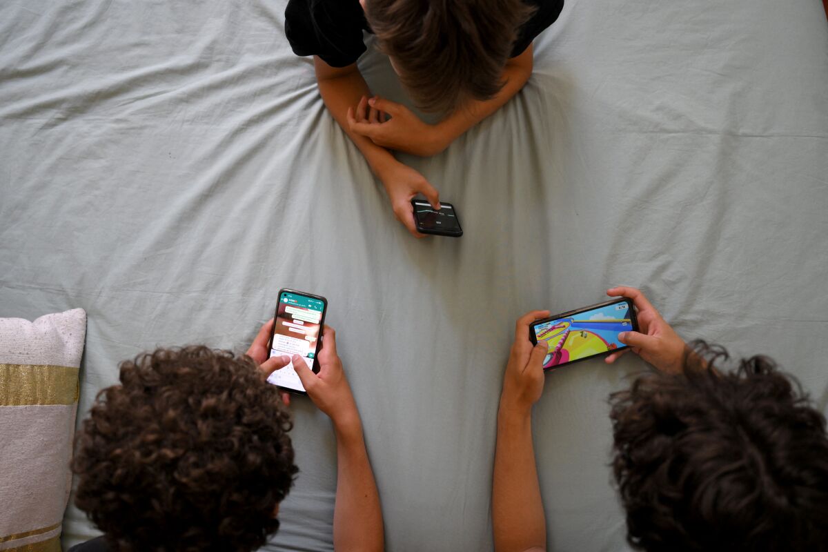 Three young people looking at their smartphones.