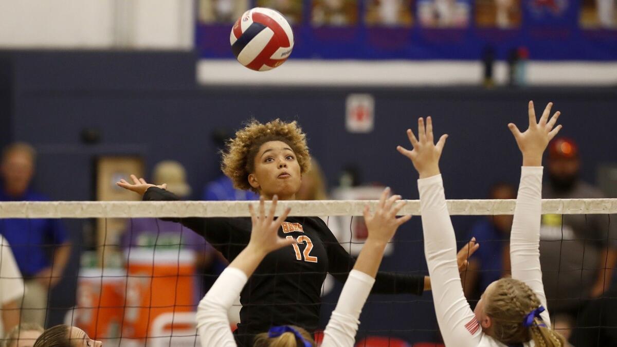 Huntington Beach High's Xolani Hodel (12) battles at the net during the second set of a Surf League match at Los Alamitos on Wednesday.