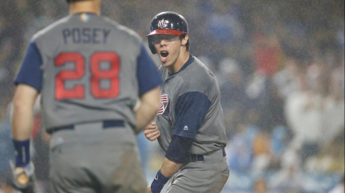 Left fielder Christian Yelich celebrates with U.S. teammate Buster Posey after scoring on a a single by Andrew McCutchen in the fourth inning of a game on March 21.