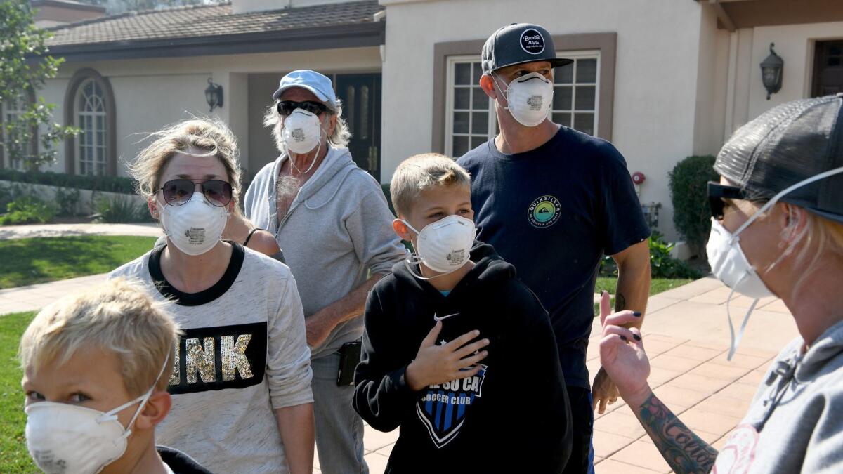 Members of the Cash family wear masks after returning to their Westlake Village neighborhood on Friday after evacuating from the Woolsey fire.