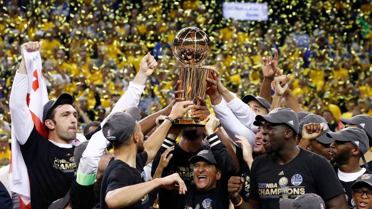 Members of the Golden State Warriors celebrate with the Larry O'Brien trophy after winning Game 5 of NBA Finals over the Cleveland Cavaliers on June 12.