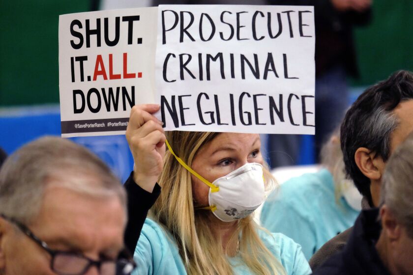 Tera Lecuona of Porter Ranch holds a protest sign during a hearing in Granada Hills over a gas leak at Southern California Gas Company's Aliso Canyon Storage Facility.