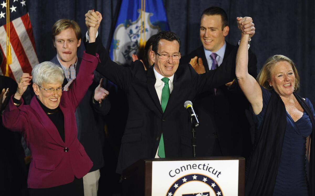 Incumbent Democratic Gov. Dannel P. Malloy, flanked by Lt. Gov. Nancy Wyman, left, and his wife, Cathy, concludes a speech to supporters at his party's rally Wednesday in Hartford, Conn.