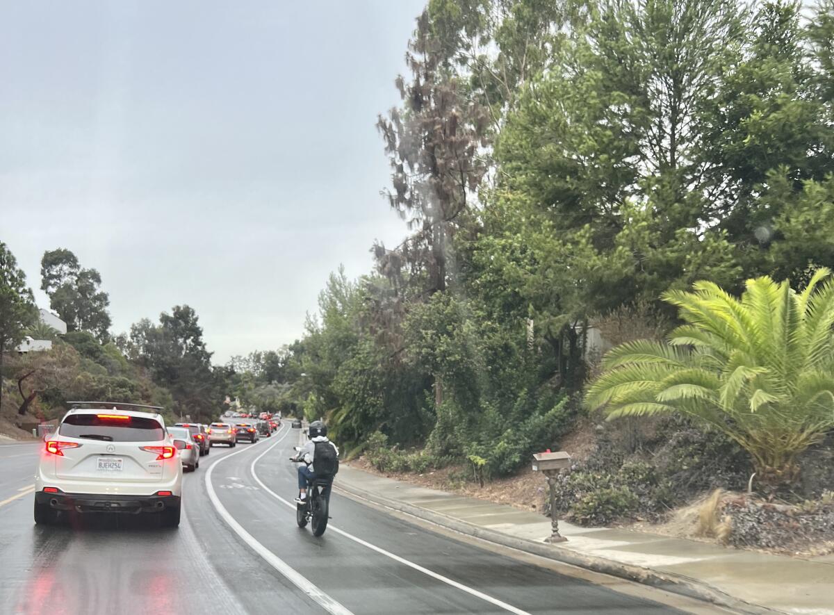 A teenager rides past stopped cars on Nautilus Street.