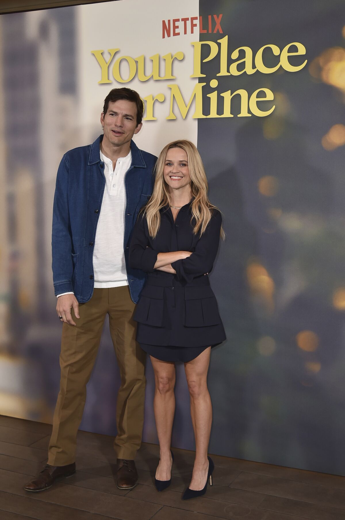 A man in a blue jacket and brown pants standing next to a woman in a black dress.
