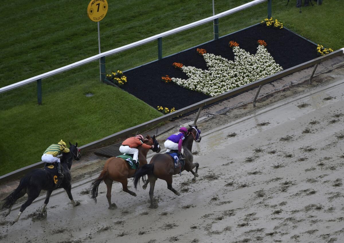 Homeboykris (3), ridden by Horacio Karamanos, heads to the finish to win the first race of the day on a muddy track ahead of the 141st Preakness Stakes on May 21.