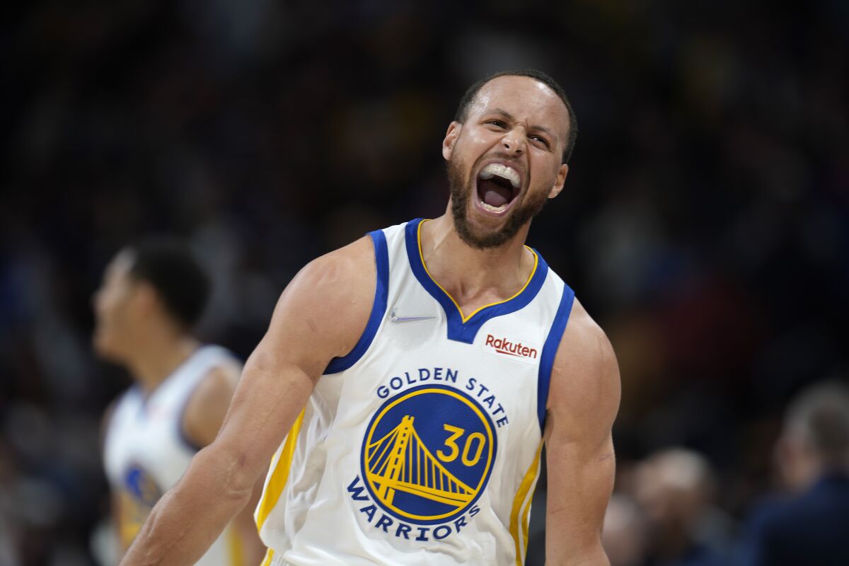 Golden State Warriors guard Stephen Curry reacts after Jordan Poole hit a 3-point basket late in the second half of the team's NBA basketball game against the Denver Nuggets on Thursday, March 10, 2022, in Denver. (AP Photo/David Zalubowski)