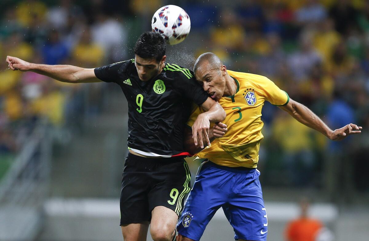 El mexicano Raúl Jiménez (izq) pelea un balón con el brasileño Miranda.