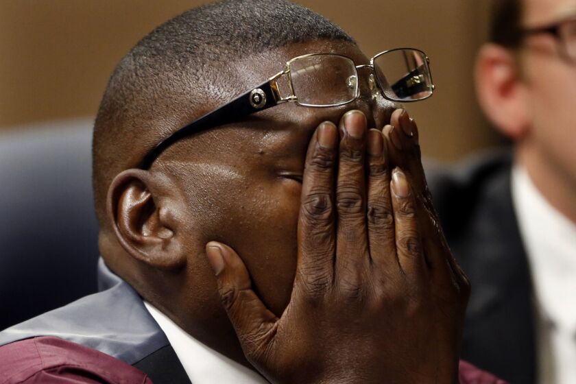Reggie Cole covers his face while he listens to testimony in a Compton court.