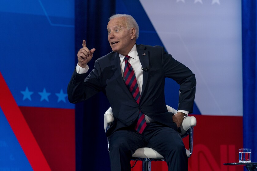 President Biden leans forward in his chair and gestures toward the audience