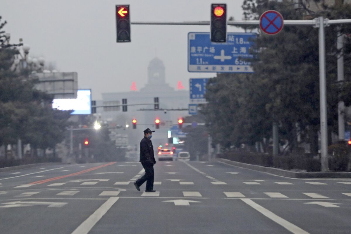 A man walks across an empty road during the fourth day of a city wide lock down in Changchun in northeastern China's Jilin province Monday, March 14, 2022. China banned most people from leaving the coronavirus-hit northeastern province and mobilized military reservists Monday as the fast-spreading "stealth omicron" variant fuels the country's biggest outbreak since the start of the pandemic two years ago. (Chinatopix Via AP) CHINA OUT