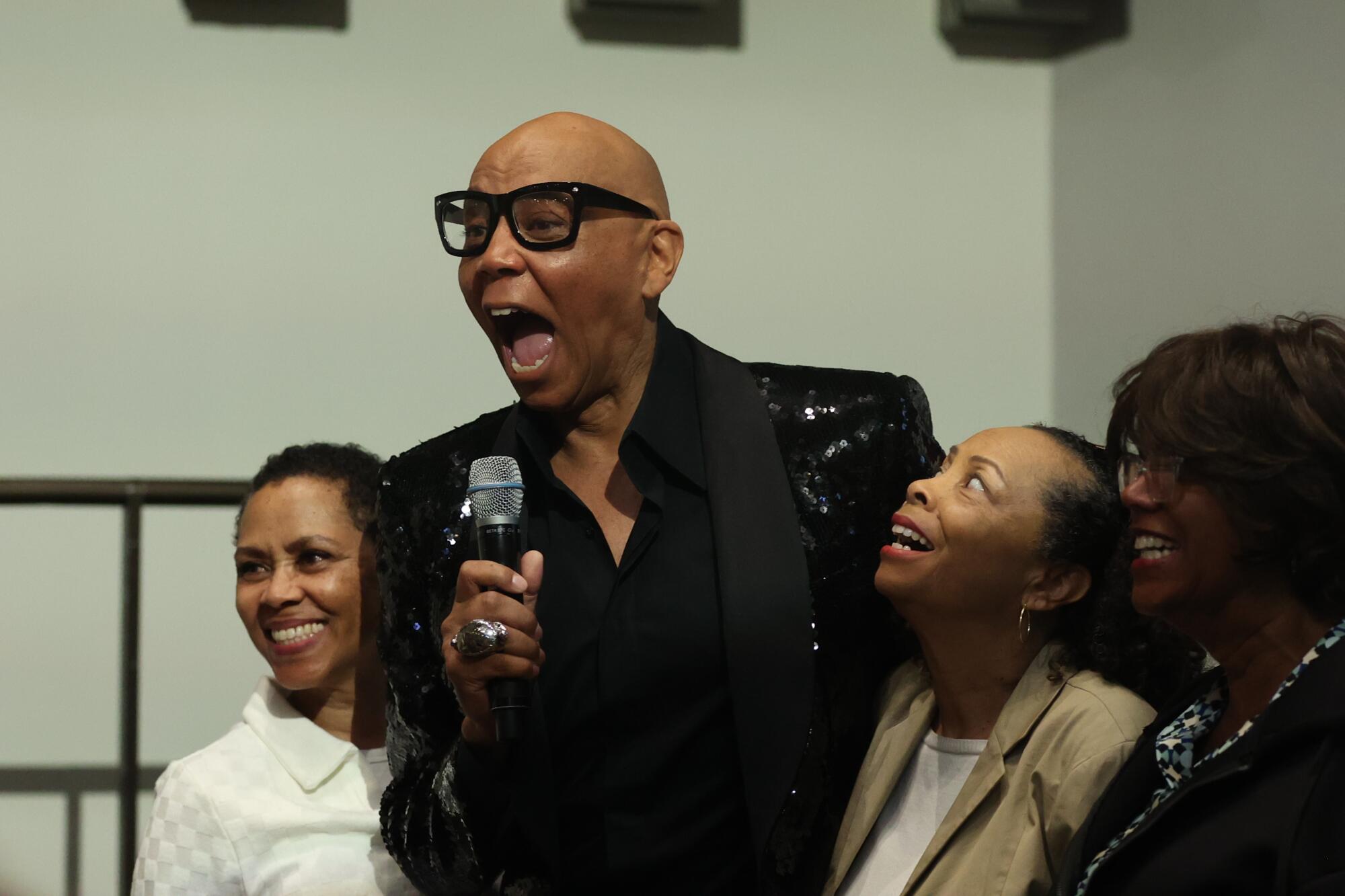 RuPaul laughs while being surrounded by his three sisters while discussing his memoir.