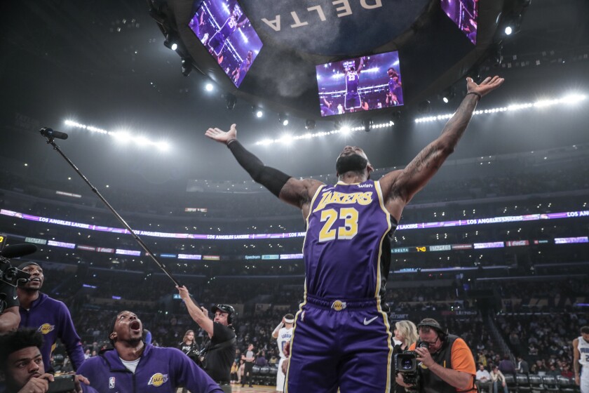 Lakers forward LeBron James claps his hands, sending talcum powder into the air, as teammates marvel at the pregame ritual.