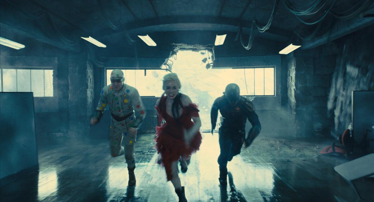A man in a polka dot suit, a woman in a dress and a man with a helmet running