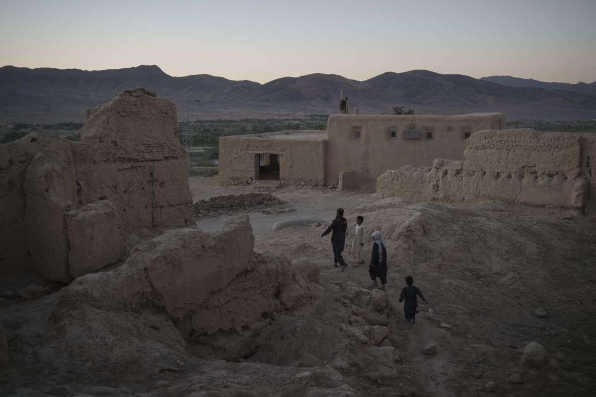 Afghans walk among the rubble of houses destroyed by fighting at a village in Wardak province, Afghanistan, Tuesday, Oct. 12, 2021. (AP Photo/Felipe Dana)
