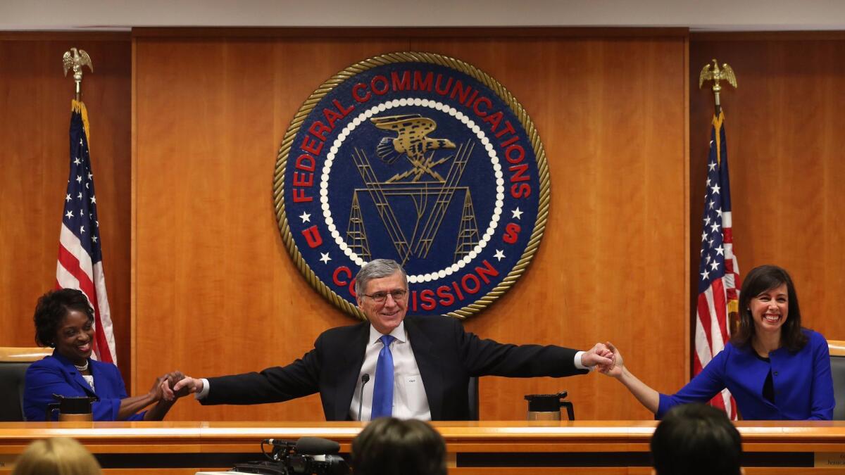 Federal Communications Commission members Mignon Clyburn, left, and Jessica Rosenworcel join hands with then-Chairman Tom Wheeler before voting for net neutrality rules in 2015.