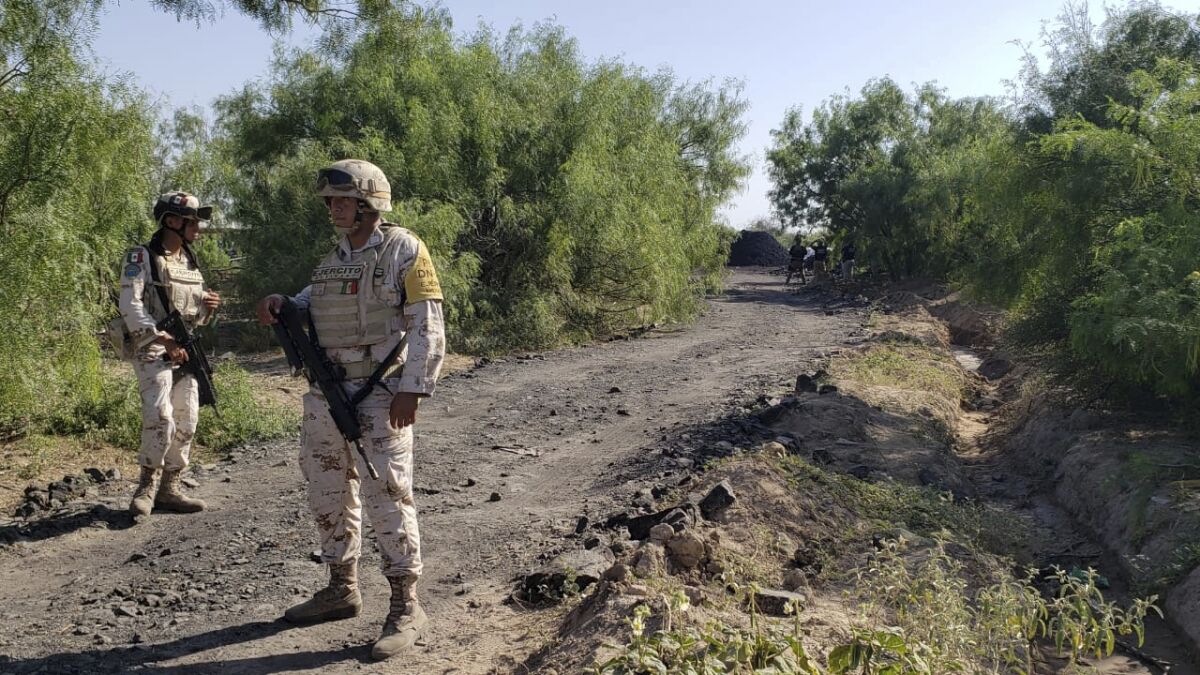 National Guards stand along the road that leads to where miners are trapped in a collapsed and flooded coal mine in Sabinas in Mexico's Coahuila state, Thursday, Aug. 4, 2022. The collapse occurred on 10 miners after they breached a neighboring area filled with water on Wednesday, officials said. (AP Photo/Elizabeth Monroy)