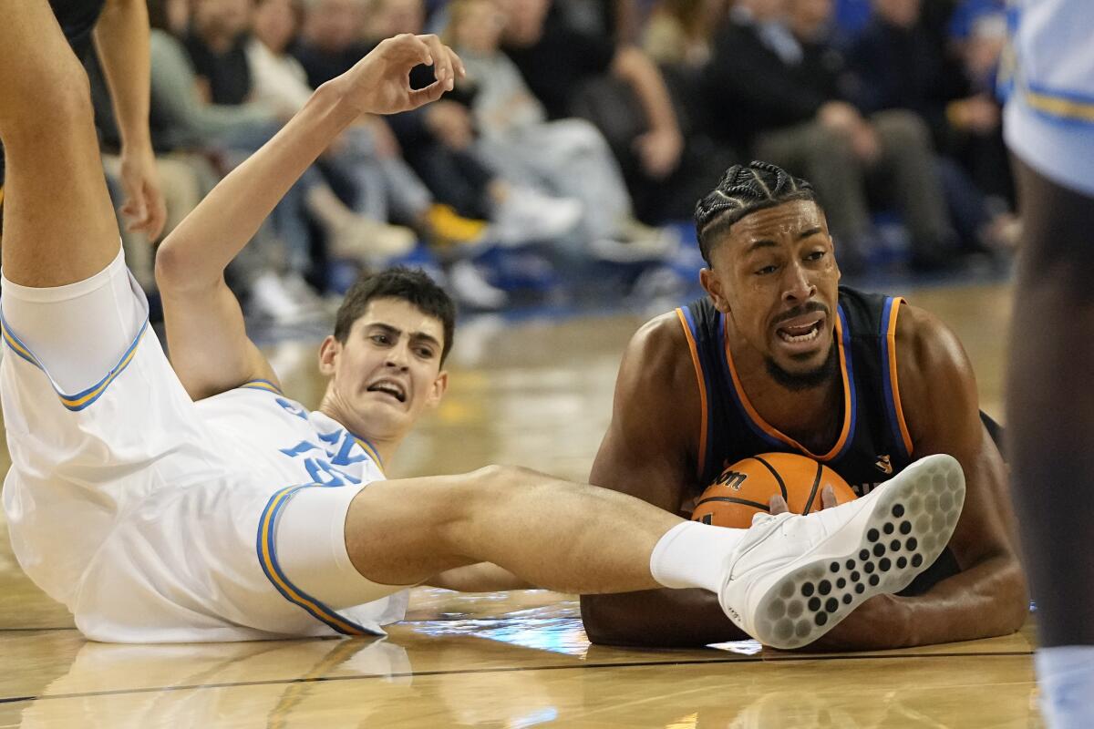 UCLA center Aday Mara and UC Riverside forward Kyle Owens scramble for a loose ball on the floor.