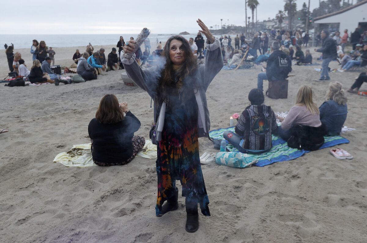 A fan burns sage to bless the drum circle remembrance at Aliso Beach in honor of Taylor Hawkins.